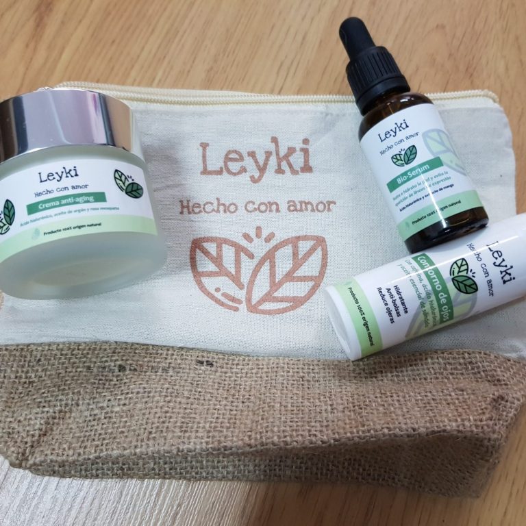 Productos de cuidado facial Leyki: crema anti aging, contorno de ojos y serum facial sobre una bolsa de tela.